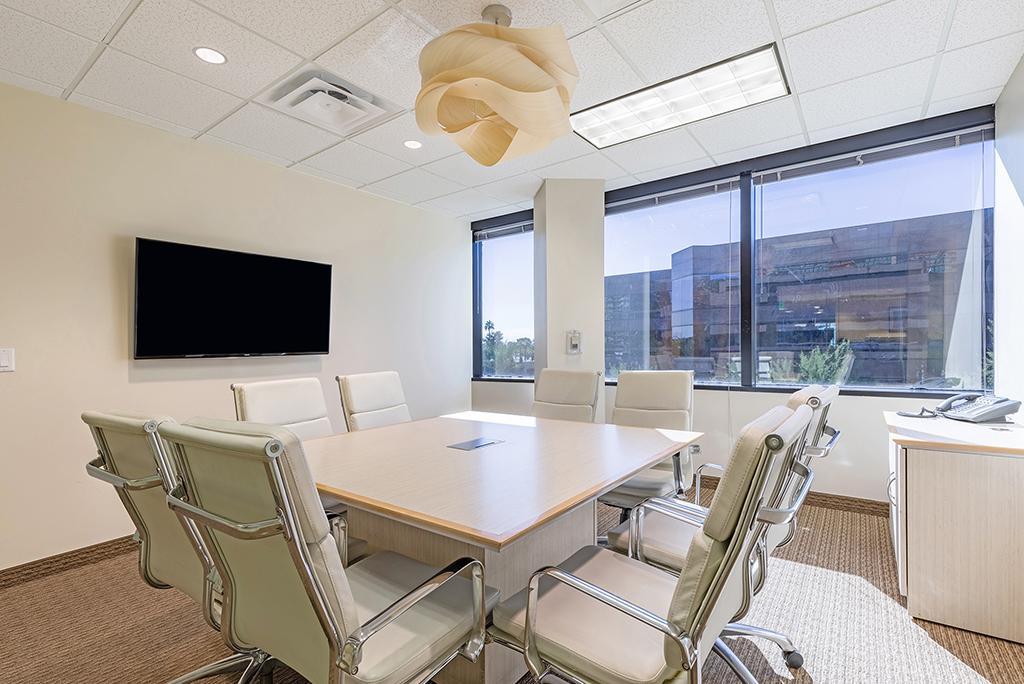 Square table with 8 chairs and AV setup and 3 windows behind